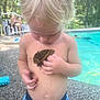 child, toddler, butterfly, pool, water, swimming_trunks, bare_chest, blonde_hair, outdoor, summer, nature, insect, curious, person, relaxation, adult, lounge_chair, trees, sunlight, backyard