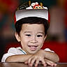 child, smiling, hat, face, hands, portrait, indoor, happy, young_child, cartoon_character, colorful, cute, person, casual_clothing, closeup, headwear, dark_hair, skin, expression, blurred_background