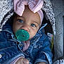 baby, pacifier, denim_jacket, blanket, headband, bow, blue_eyes, close_up, infant, cute, warm_clothing, child, car_seat, soft_texture, pink, cozy, portrait, small_hands, outdoor, face
