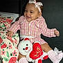 baby, child, teddy_bear, pink_clothing, headband, smile, couch, blanket, floral_pattern, toy, socks, cute, happy, indoor, portrait, infant, soft_toy, seated, lace, red_heart