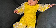 Javeah joined the competition — help win amazing prizes! baby, child, yellow_outfit, headband, blue_eyes, couch, gray_cushions, daisy_pattern, sitting, barefoot, curly_hair, indoor, portrait, cute, fashion, comfortable, relaxed, smiling, person, soft_lighting