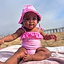 baby, child, swimsuit, pink, hat, beach, towel, sand, sunhat, outdoor, portrait, sitting, infant, cute, summer, person, young_child, sun_protection, relaxing, vacation