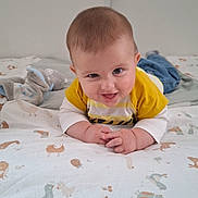 Jules participe au concours pour gagner de l'argent avec cette photo : animal_print, baby, bed, blanket, blue_pants, child, cute, face, hands, home, indoor, infant, lying_down, person, playful, smiling, soft_toy, tongue_out, white_clothing, yellow_clothing