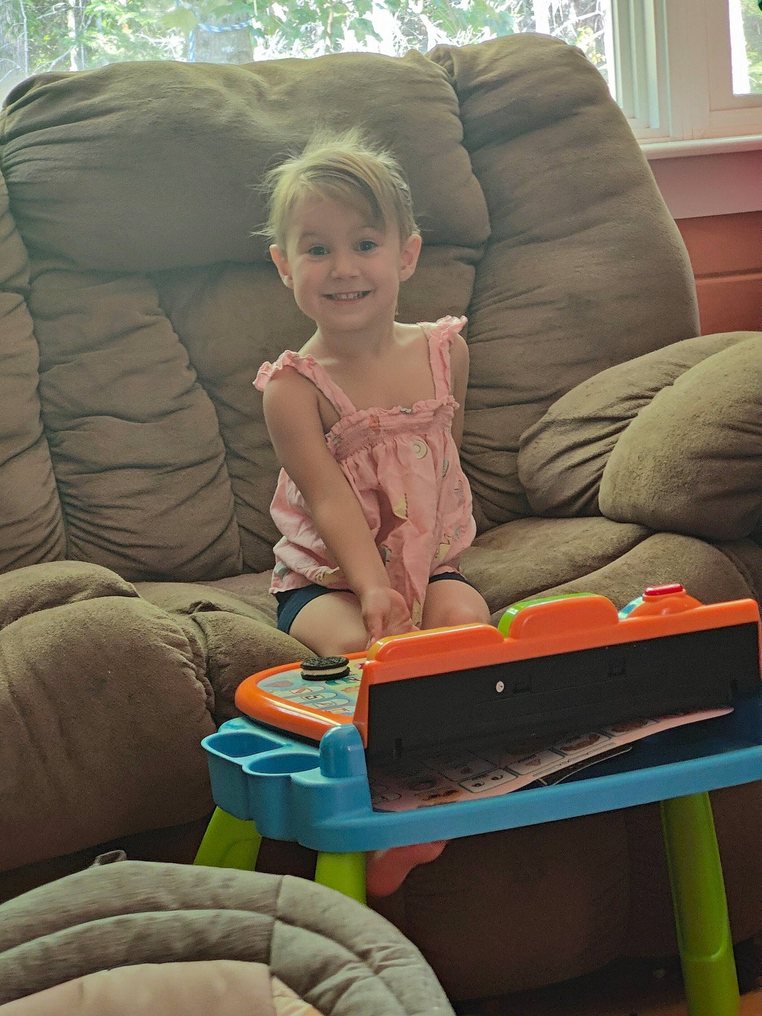 Marissa is registered to the contest to win money with this photo: arm, comfort, couch, electronic_device, finger, fun, gadget, human_body, human_leg, joy, lap, leisure, living_room, musical_instrument, person, room, sitting, smile, thigh, toddler