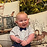 baby, child, smiling, bow_tie, shirt, couch, pillow, holiday_decor, christmas_tree, lights, deer, sleigh, indoor, cozy, festive, infant, happy, plush, home, portrait