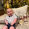 Ashton joined the competition — help win amazing prizes! baby, child, smiling, sitting, carpet, pillow, reindeer, christmas_tree, ornaments, lights, milestone_marker, indoor, holiday, decorations, cute, festive, clothing, shorts, shirt, bow_tie