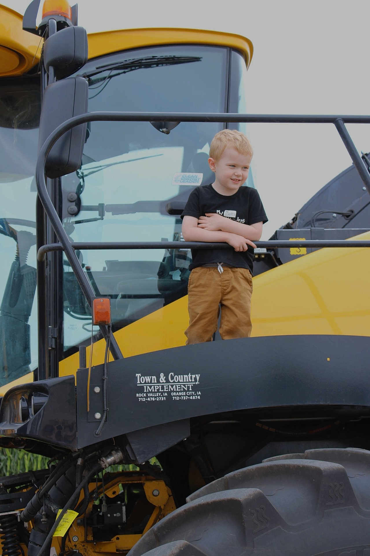 Oliver joined the competition — help win amazing prizes! child, boy, smiling, yellow_vehicle, tractor, agriculture, large_tire, outdoor, machinery, black_rail, clothing, short_sleeve_shirt, pants, blonde_hair, standing, daylight, farm_equipment, vehicle, happy, metal