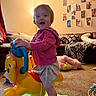Ashlynn joined the competition — help win amazing prizes!  smiling, carpet, child, colorful, couch, family_photos, happy, home, horse_toy, indoor, living_room, pillows, pink_hoodie, playtime, portrait, ride_on_toy, skirt, standing, toddler, toy