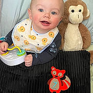 Zander is registered to the contest to win money with this photo: baby, infant, bib, toy, stuffed_monkey, blue_eyes, smile, blanket, plush, hand, play_toy, ring_toy, fox_sticker, number_7, nursery, portrait, rosy_cheeks, onesie, sitting, soft_toy