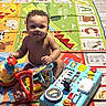 toddler, child, toy, play_mat, colorful, indoor, floor, piano_toy, ride_on_toy, bumper_car, smiling, curly_hair, baby, playtime, learning, alphabet, animal_pictures, plastic_toys, happy, young_child