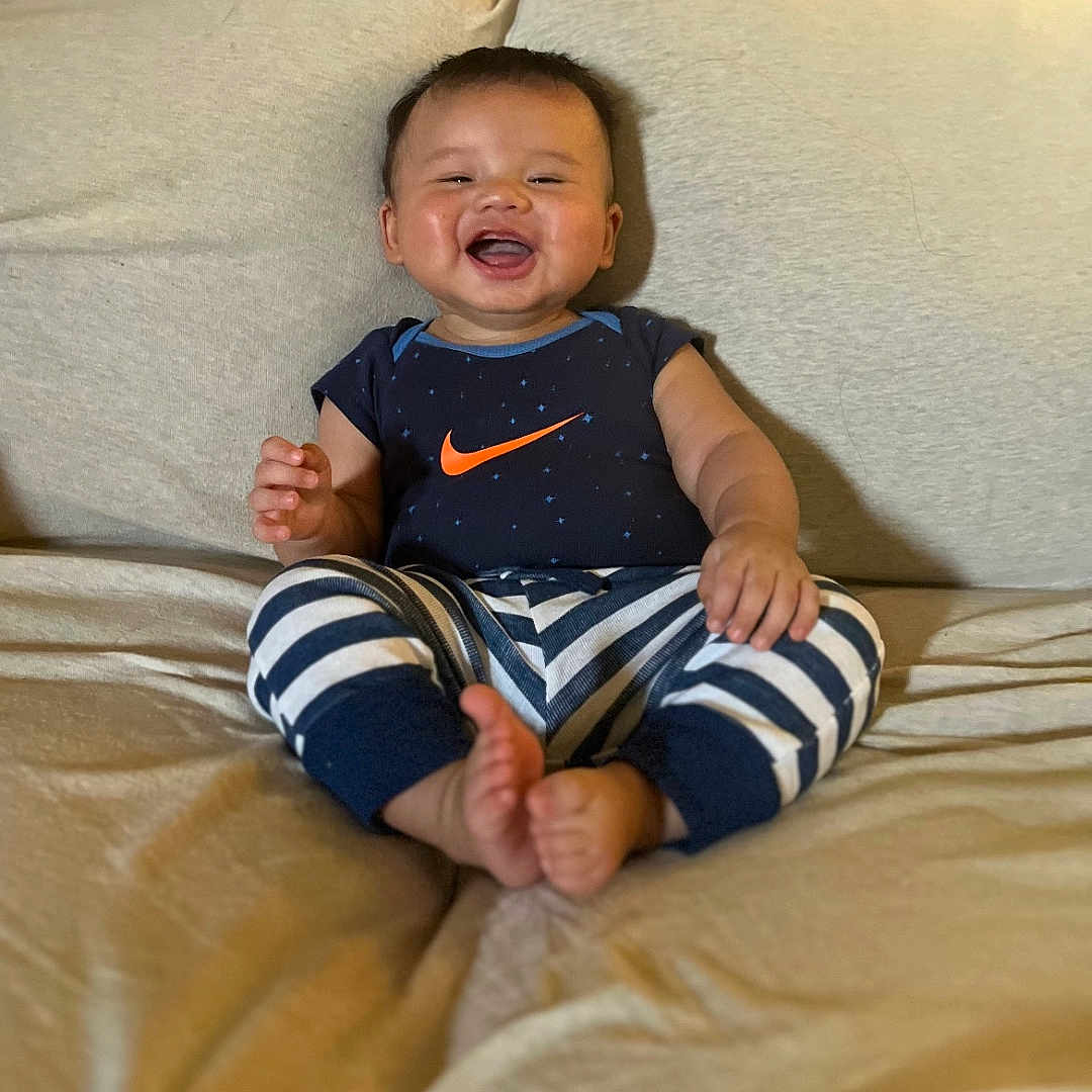 David is registered to the contest to win money with this photo: baby, babylaughing, bed, bedroom, clothing, couch, cushion, face, furniture, happy, head, homedecor, indoors, laughing, pants, person, photography, portrait, room, t_shirt