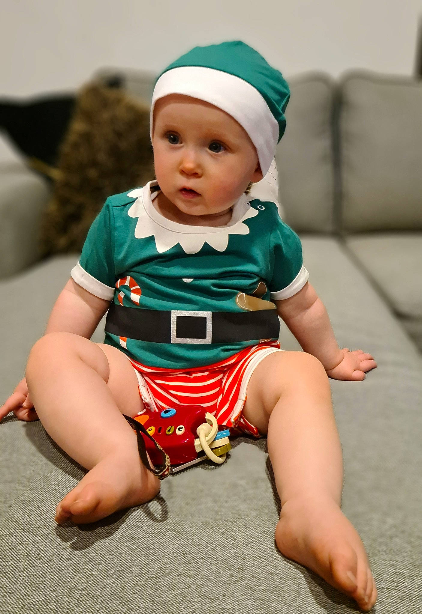 Maia is registered to the contest to win money with this photo: baby, baby_toddler_clothing, cap, child, comfort, couch, event, face, foot, happy, headwear, holiday, human_leg, knee, person, shorts, sitting, sleeve, t_shirt, thigh