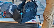 Vicky a rejoint le concours — aidez-le/la à gagner de superbes lots ! bag, bench, black_dog, brown_shoes, curious, dog, floor, hand, indoor, leash, luggage, modern, pants, person, seat, shoes, train_station, travel, waiting, waiting_area