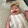 Londyn is registered to the contest to win money with this photo: baby, infant, smiling, headband, bow, striped_clothing, blanket, soft_texture, happy, cute, portrait, child, laying_down, indoors, skin, face, arm, small_hand, cheerful, comfortable