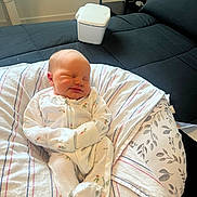 Londyn is registered to the contest to win money with this photo: baby, newborn, infant, sleeping, onesie, blanket, pillow, couch, furniture, indoors, peaceful, cozy, soft, striped, floral, person, child, resting, cute, home
