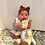 baby, child, headband, bow, plush_toy, stuffed_animal, dog_toy, blanket, floral, cute, sitting, indoors, soft_toy, playful, infant, young_child, chewing, person, white_background, clothing