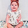 baby, child, blue_eyes, headband, bow, dress, giraffe_print, sitting, blanket, toy, wooden_toy, cute, happy, smiling, indoors, soft_lighting, plush_blanket, infant, chubby_cheeks, portrait