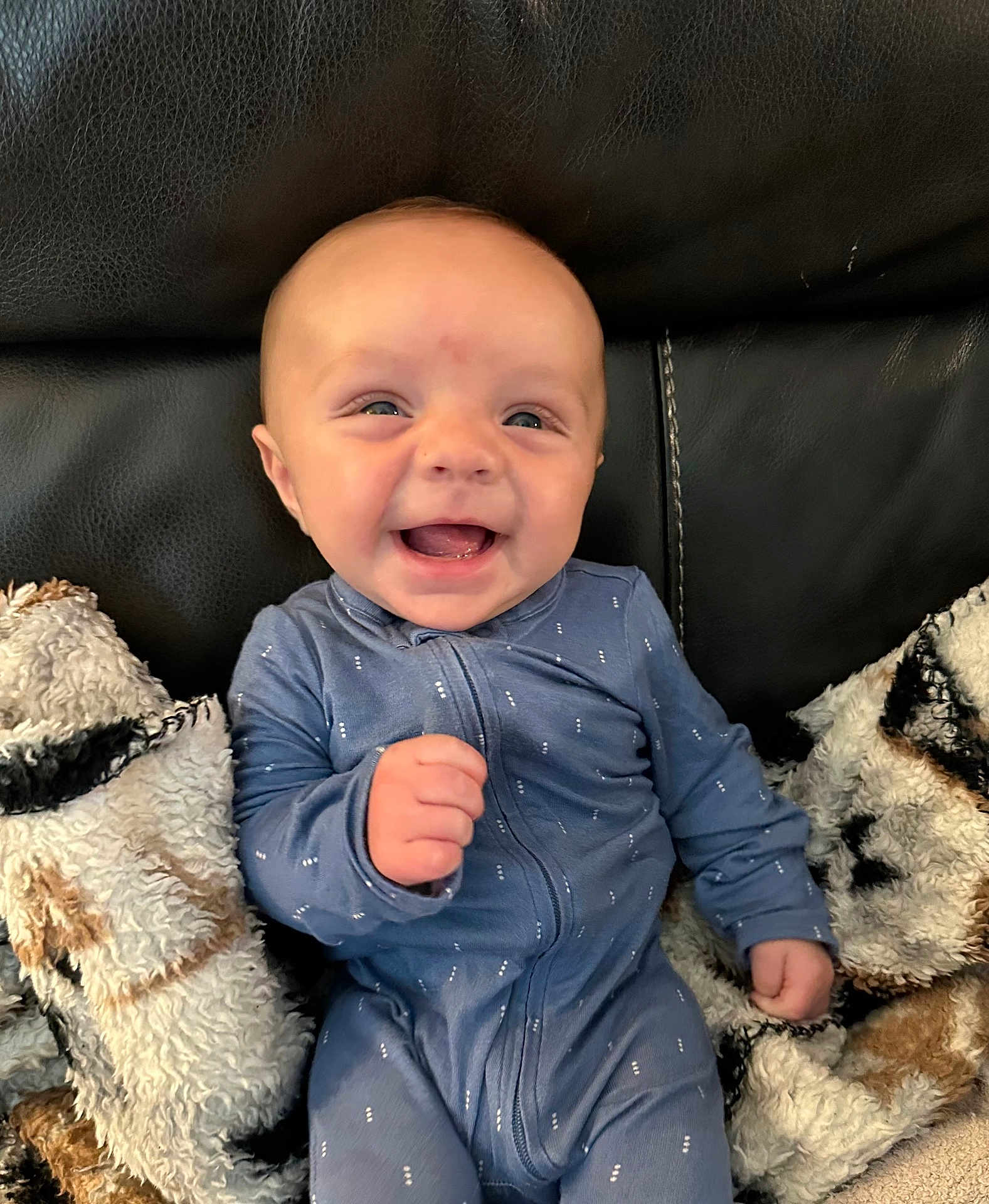 Kohen joined the competition — help win amazing prizes! baby, smiling, blue_onesie, blanket, couch, leather, happy, infant, child, cozy, soft, furniture, portrait, sitting, cute, young_child, indoors, comfort, warm, expression