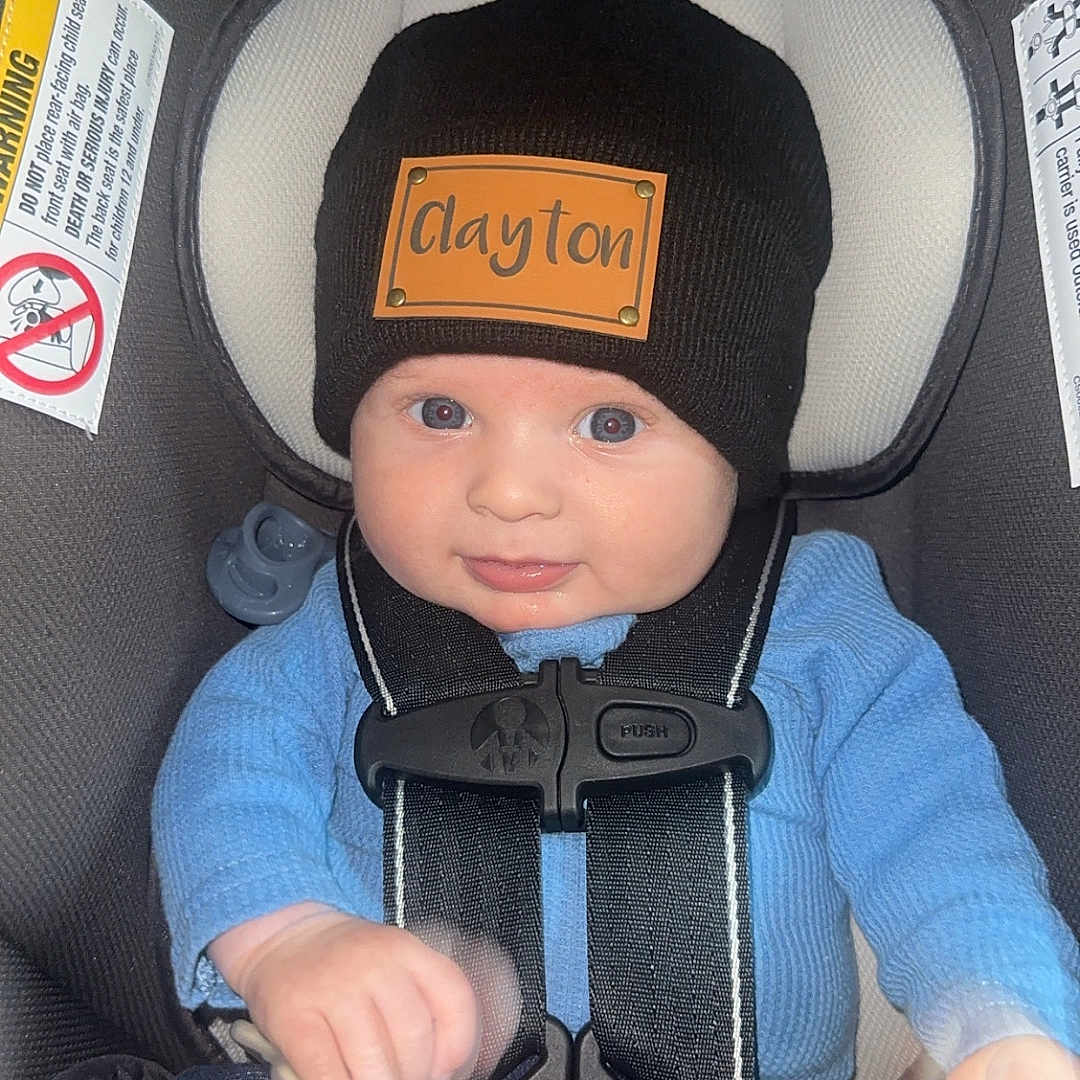 Clayton joined the competition — help win amazing prizes! baby, black_hat, blue_sweater, car_seat, child, child_safety, clothing, cute, face, hat, headwear, holding, indoor, infant, pacifier, person, portrait, safety, seatbelt, smile