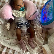 Clementine is registered to the contest to win money with this photo: baby, blanket, bow, child, cute, floral_bib, headband, indoors, infant, lights, neck_pillow, pacifier, patterned_blanket, plush, relaxed, socks, soft_toys, striped_clothing, toy, unicorn