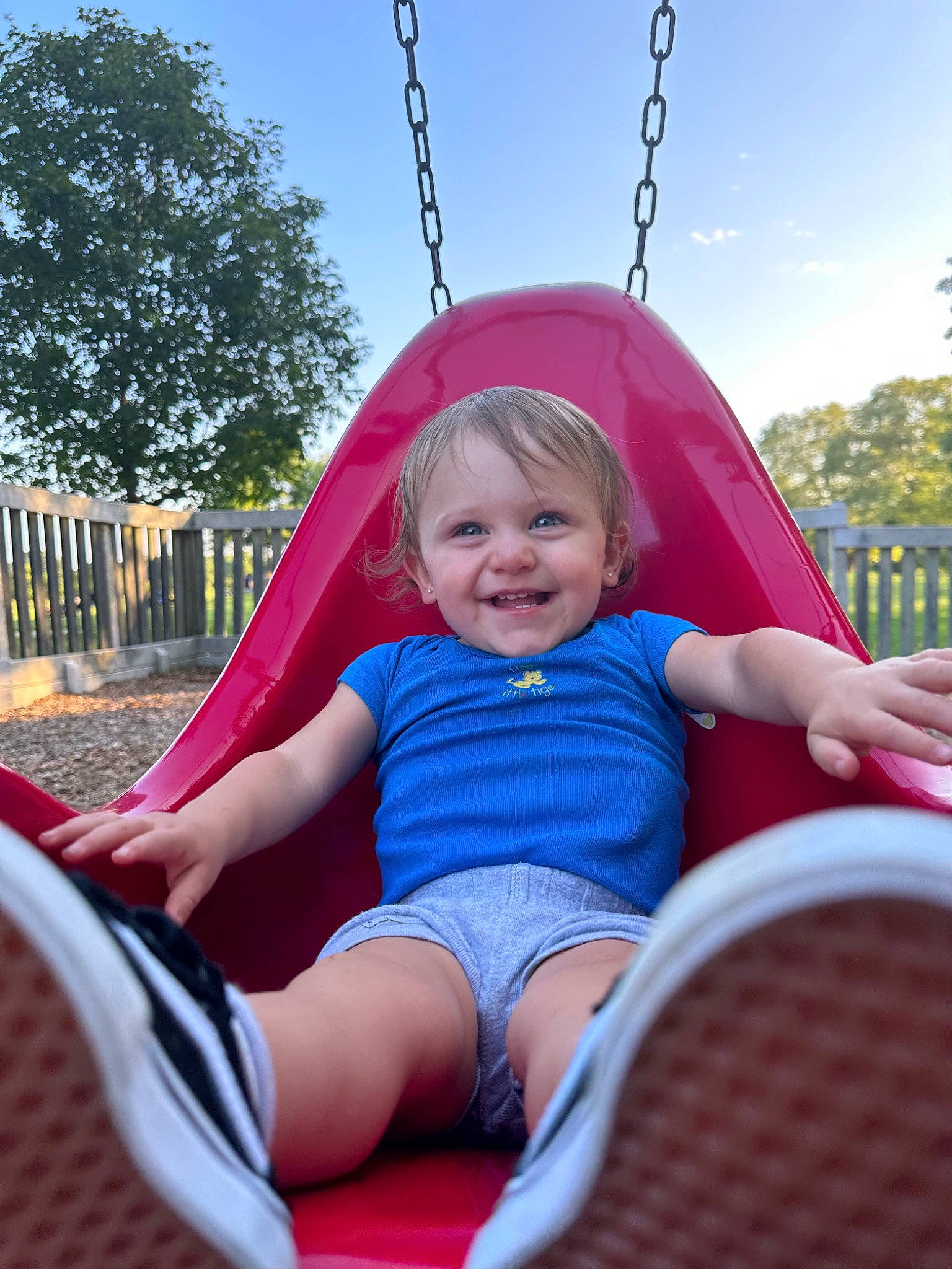 Esmé is registered to the contest to win money with this photo: arm, baby_toddler_clothing, blue, comfort, facial_expression, fun, grass, happy, human_body, joy, leisure, person, pink, playground, public_space, red, shorts, sky, smile, summer