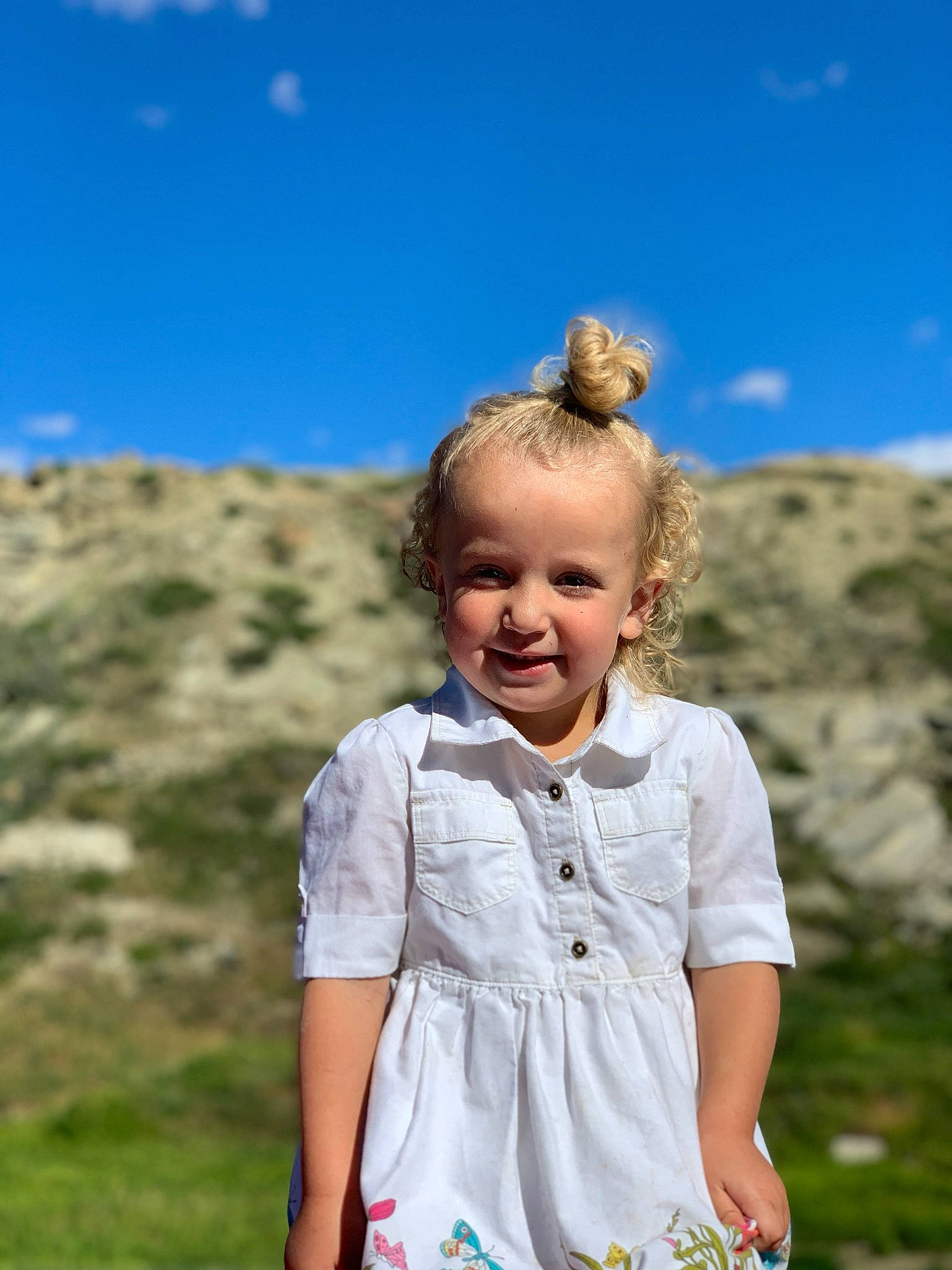 Hadleigh is registered to the contest to win money with this photo: blond, blue, child, dress, fun, grass, happy, joy, mountain, people, people_in_nature, person, photography, shoulder, sky, sleeve, smile, spring, summer, toddler