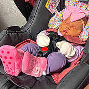 Lily is registered to the contest to win money with this photo: baby, infant, newborn, sleeping, car_seat, harness, headband, bow, patterned_pillow, mittens, pink_booties, purple_pants, carseat_padding, safety_label, evenflo_brand, closeup, indoor, textured_wall, portrait, adorable