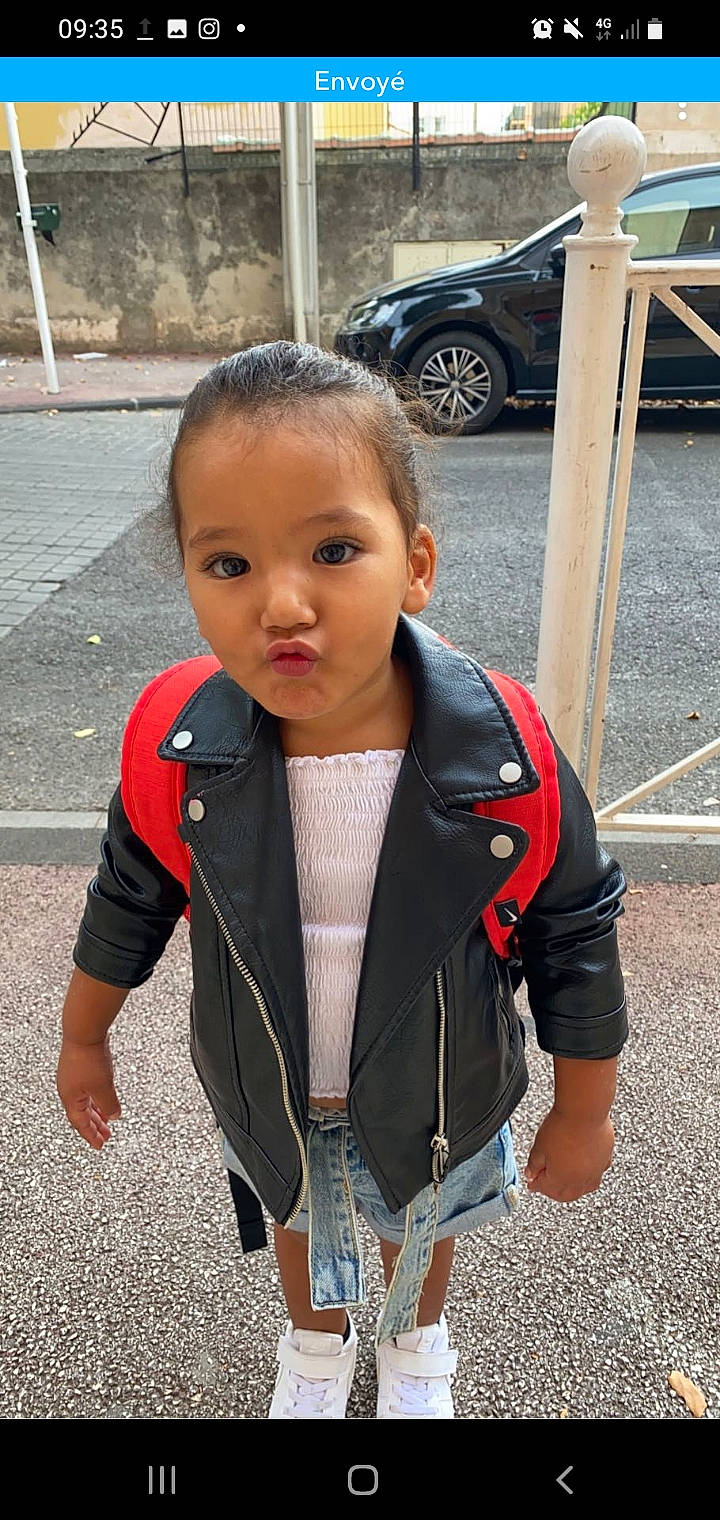 Meryem a rejoint le concours — aidez-le/la à gagner de superbes lots ! asphalt, automotive_tire, baby_toddler_clothing, child, chin, fashion_accessory, hair, hairstyle, head, jewellery, necklace, person, personal_protective_equipment, road, road_surface, sidewalk, sleeve, street_fashion, t_shirt, toddler