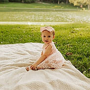 Kora joined the competition — help win amazing prizes! baby, child, girl, pink_dress, bow, blanket, grass, lake, outdoor, nature, smile, portrait, sitting, cute, sunlight, greenery, young_child, headband, happy, summer