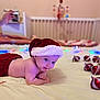 baby, bed, blanket, child, christmas, crib, cute, festive, holiday, holiday_decor, indoors, infant, nursery, ornaments, red_clothing, santa_hat, smiling, soft_lighting, string_lights, tummy