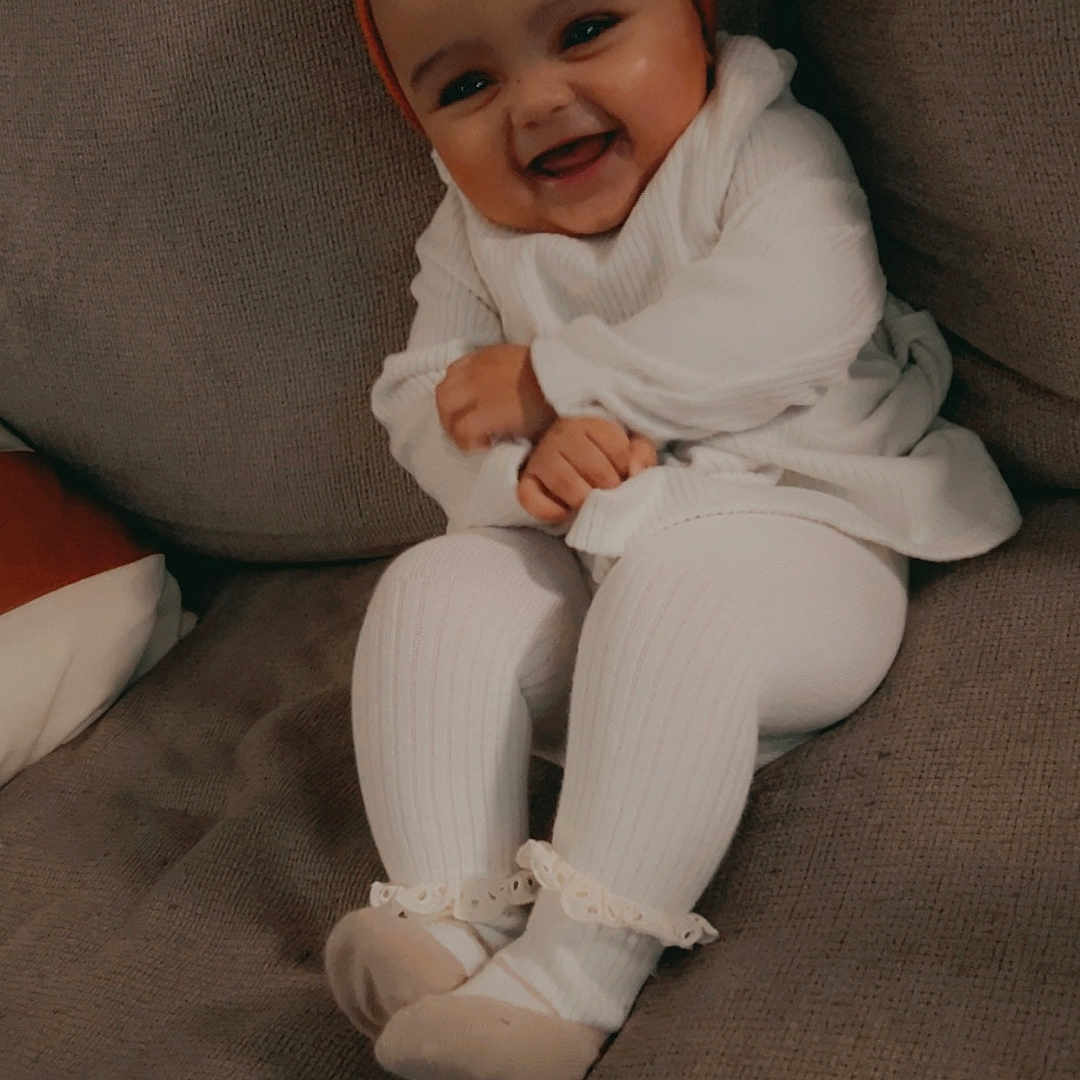 Lailani joined the competition — help win amazing prizes! baby, babylaughing, bonnet, cap, clothing, couch, face, furniture, happy, hat, head, hosiery, laughing, pants, person, photography, portrait, sitting, smile, sock