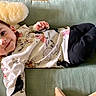 Sebastian is registered to the contest to win money with this photo: baby, child, smile, lying_down, cushion, pillow, shirt, pants, indoor, comfort, happy, face, person, cute, young, cozy, clothing, infant, resting, playful