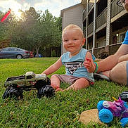 Sabastian Kiefer joined the competition — help win amazing prizes! child, toddler, grass, toy, monster_truck, outdoor, sunset, adult, building, car, blue_shirt, shorts, glasses, smile, playing, nature, greenery, daylight, relaxation, fun