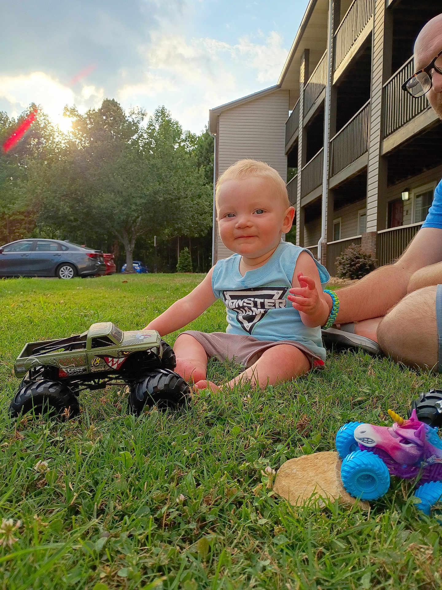 Sabastian Kiefer joined the competition — help win amazing prizes! child, toddler, grass, toy, monster_truck, outdoor, sunset, adult, building, car, blue_shirt, shorts, glasses, smile, playing, nature, greenery, daylight, relaxation, fun