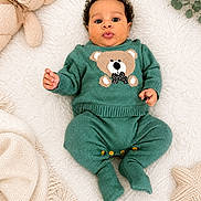 Noah is registered to the contest to win money with this photo: baby, infant, green_clothing, knitwear, teddy_bear, blanket, soft_texture, plush_toy, star_shaped_pillow, indoor, cute, portrait, lying_down, child, adorable, cozy, warm, hands, face, expression