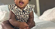 Jaliyah joined the competition — help win amazing prizes! baby, child, infant, bed, blanket, clothing, curly_hair, cute, face, hair_bows, indoors, leopard_print, person, portrait, sitting, skin, soft_lighting, white_bed, young_child, expression