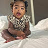 baby, child, infant, bed, blanket, clothing, curly_hair, cute, face, hair_bows, indoors, leopard_print, person, portrait, sitting, skin, soft_lighting, white_bed, young_child, expression