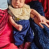 adult_hand, baby, bib, blanket, blue_fabric, blue_pants, closeup, clothing, cozy, cute, finger, hand, indoors, infant, newborn, pink_socks, red_fabric, resting, sleeping, soft
