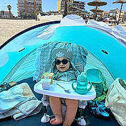 Ayden participe au concours pour gagner de l'argent avec cette photo : baby, bag, beach, child, footwear, highchair, outdoor, playful, relaxation, sand, shade, sippy_cup, snack, summer, sunglasses, sunhat, sunny, tent, towel, vacation