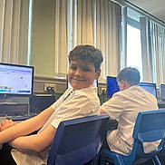 Janduel is registered to the contest to win money with this photo: child, boy, student, classroom, computer, monitor, desk, chair, school_uniform, smile, curly_hair, blinds, window, school, keyboard, mouse, seat, backpack_area, student_working, technology