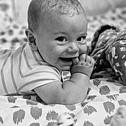 Loann participe au concours pour gagner de l'argent avec cette photo : baby, infant, smiling, black_and_white, patterned_blanket, lying_down, cute, portrait, child, hand_in_mouth, soft_toys, close_up, happy, cheeks, striped_clothing, bed, indoors, candid, young_child, face