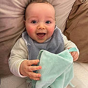 Tyméo participe au concours pour gagner de l'argent avec cette photo : baby, bib, blanket, cheeks, child, clothing, couch, cozy, eyes, fingers, hand, happy, infant, mouth_open, nursery, pillow, portrait, sitting, smile, soft_toy