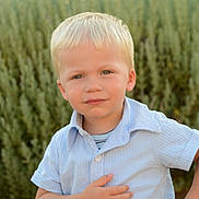 Leo a rejoint le concours — aidez-le/la à gagner de superbes lots ! child, toddler, blond_hair, blue_shirt, outdoor, greenery, portrait, young_child, curious_expression, nature, casual_clothing, standing, daylight, short_sleeves, person, face, hands, garden, summer, cute