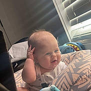 Hudson is registered to the contest to win money with this photo: baby, infant, pillow, blanket, window, blinds, toy, indoor, child, person, cute, smiling, sitting, soft, light, home, cozy, face, expression, clothing
