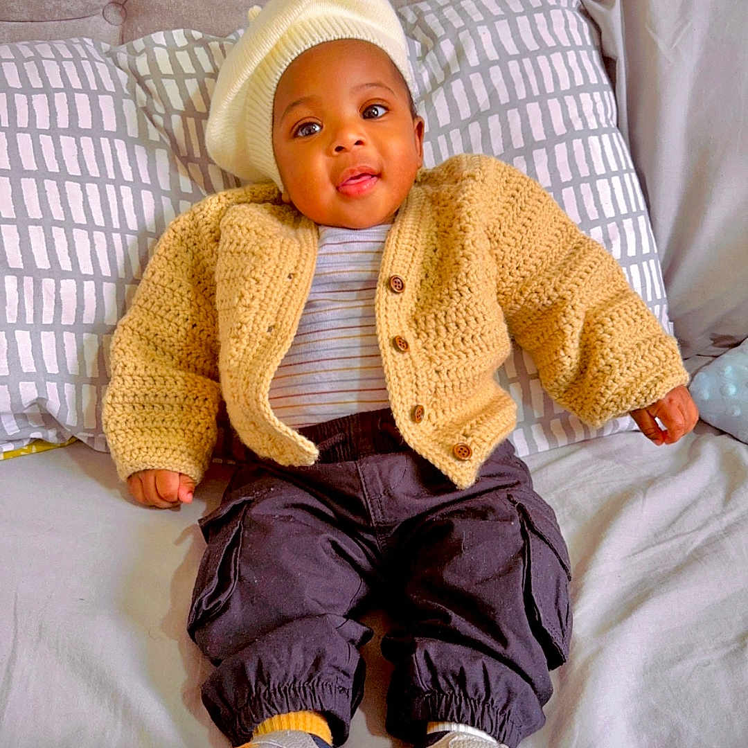 Efua joined the competition — help win amazing prizes! baby, bonnet, cap, clothing, couch, cushion, face, footwear, furniture, hat, head, jeans, knitwear, pants, person, photography, portrait, shoe, sitting, sweater
