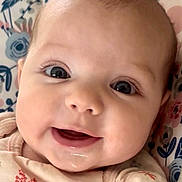 Sophia joined the competition — help win amazing prizes! baby, infant, face, smile, eyes, close_up, child, cute, expression, skin, mouth, clothing, floral_pattern, cushion, portrait, young, happy, cheeks, person, indoors