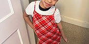 Nevaeh Adames is registered to the contest to win money with this photo: child, girl, red_dress, plaid, white_tshirt, sandals, carpet, door, indoor, smile, pose, standing, person, young, fashion, hair_tied_back, happy, portrait, cute, casual