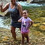 woman, child, stream, water, rocks, thumbs_up, smile, outdoor, nature, cap, shorts, tshirt, happy, family, summer, play, fun, shallow_water, rocky_shore, posing