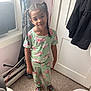 child, girl, smile, braids, pajamas, floral_pattern, indoor, carpet, door, window, curtain, sneakers, colorful_shoes, standing, young, person, happy, casual_clothing, home, portrait