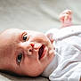 Leo is registered to the contest to win money with this photo: baby, infant, face, eyes, mouth, skin, clothing, white_onesie, lying_down, close_up, cute, newborn, child, human, portrait, expression, soft_light, indoors, happy, small